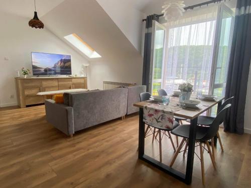 a living room with a couch and a table with chairs at Apartament Bieszczady in Hoczew