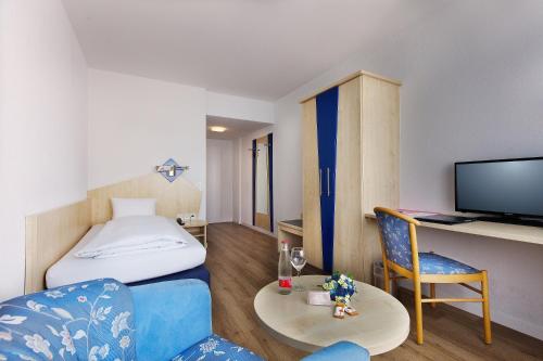 ein Hotelzimmer mit einem Bett, einem Tisch und Stühlen in der Unterkunft Hotel Blumenstein Self-Check In in Frauenfeld
