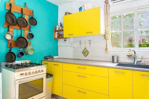 a kitchen with yellow cabinets and a white stove at The White Hill Guesthouse in Yeroẖam