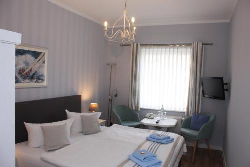 a bedroom with a bed and two chairs and a television at Hotel Maria in Greifswald