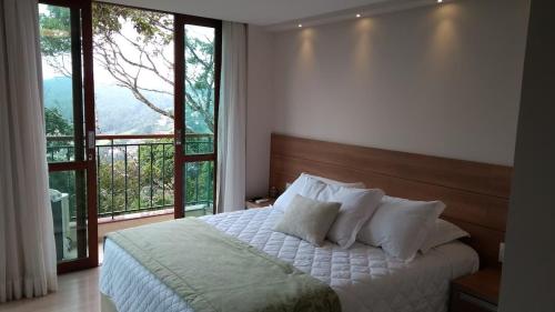 a bedroom with a bed and a large window at Flat Vista Azul Hotel in Pedra Azul