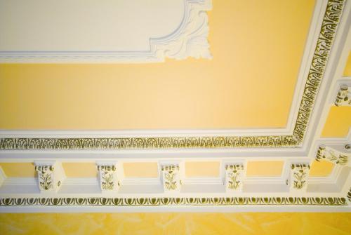 a room with a yellow wall with a white ceiling at Hotel Tuscolana in Rome
