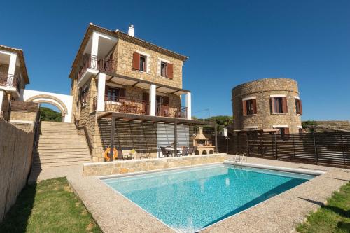 a house with a swimming pool in front of a building at Armonia Seaside Villas in Vasilikos