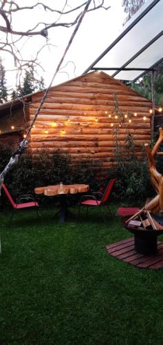 a picnic table and chairs in front of a wooden wall at Cabaña en la Calera el Pinar in La Calera