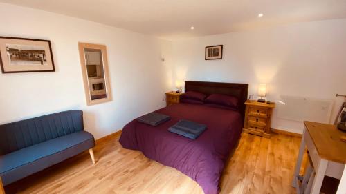 a bedroom with a bed and a blue couch at Private Detached Annex in Isleham Village in Isleham
