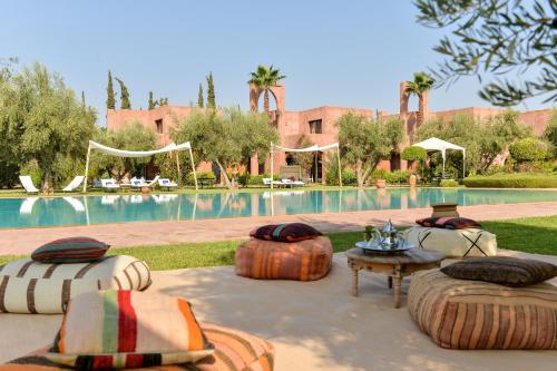 a resort with a pool with large pillows and a table at Les Jardins De Zyriab in Aït Hamid