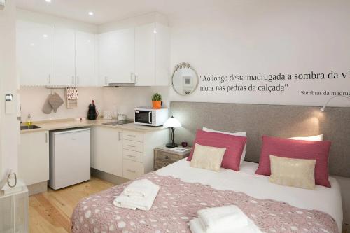 a bedroom with a bed with pink pillows and a kitchen at Central Studio in Lisbon