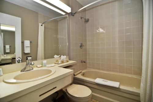 a bathroom with a sink and a toilet and a tub at Aurora Inn in Kingston