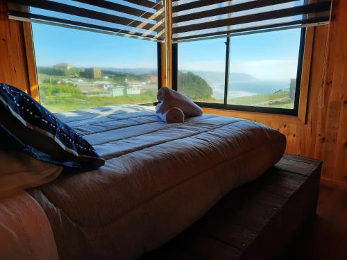 una cama con un oso de peluche sentado en ella frente a una ventana en Palmar Matanzas en Boca Pupuya