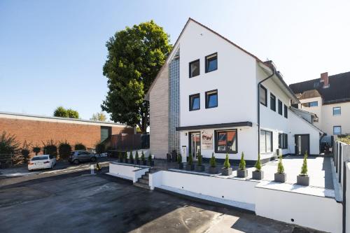 een wit gebouw met potplanten op een parkeerplaats bij StayStay Guesthouse I 24 Hours Check-In in Neurenberg