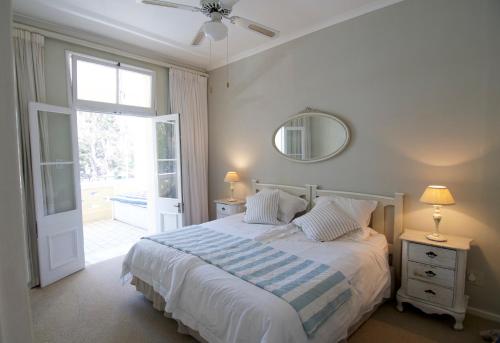 1 dormitorio con cama, ventana y espejo en On The Square Luxury Apartment en Simonʼs Town