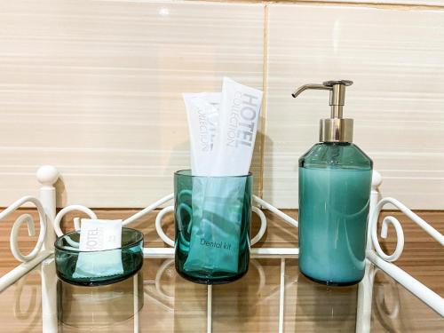 a bottle of soap and two glasses on a glass table at Hotel G.S. in Novokuznetsk