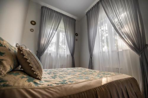 a bedroom with a bed and two windows with curtains at Baltic Sea Dunes Apartments in Jūrmala