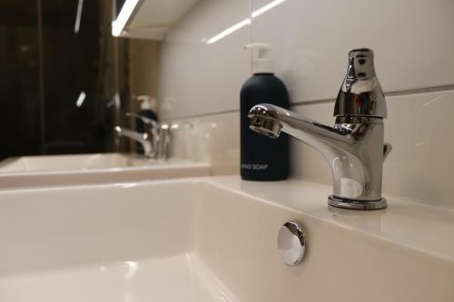 a bathroom sink with a faucet and a bottle of wine at Apartmenthaus Hinterer in Bad Goisern