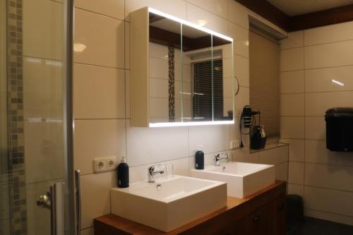 a bathroom with two sinks and a mirror at Apartmenthaus Hinterer in Bad Goisern