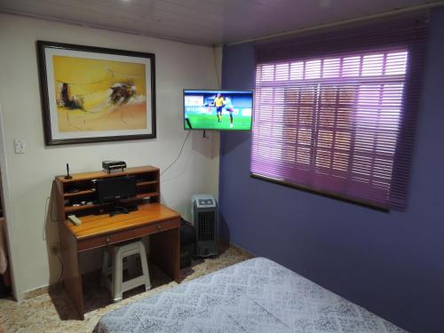 um quarto com uma secretária e uma televisão num quarto em MZ Hostel em Campo Grande