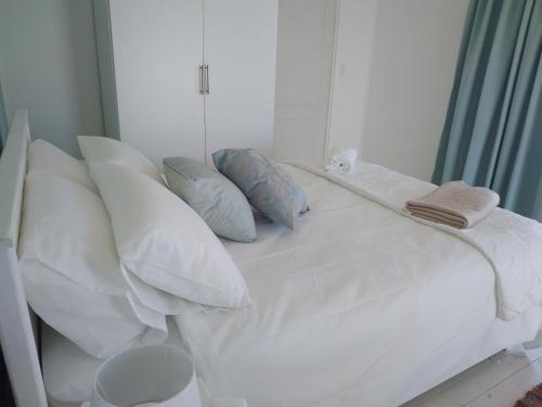 Una cama blanca con almohadas y una toalla. en CoCo de Mer Self Catering Log 1, en Lambertʼs Bay