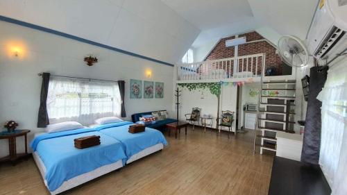 ein großes Schlafzimmer mit einem blauen Bett und einer Küche in der Unterkunft Tip House in Khao Kho