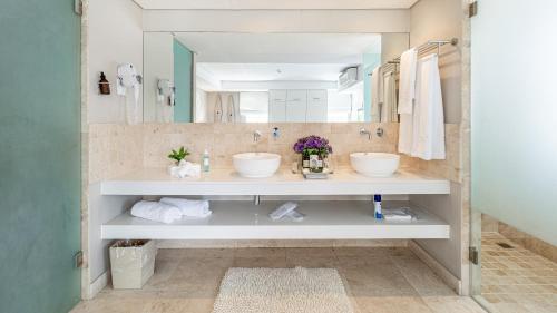 a bathroom with two sinks and a large mirror at The Glen Boutique Hotel & Spa in Cape Town