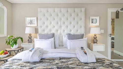 a bedroom with a large white bed with two lamps at The Glen Boutique Hotel & Spa in Cape Town