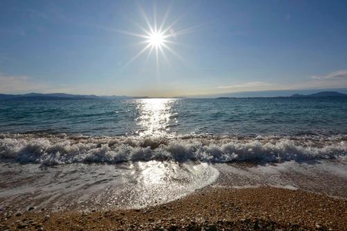 a beach with the sun rising over the ocean at Renata Rooms & Studios in Barbati