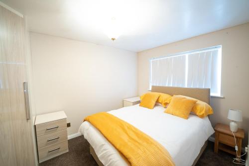 um quarto com uma cama com almofadas amarelas e uma janela em Longley Farm View -spacious 3 Bed Property em Sheffield