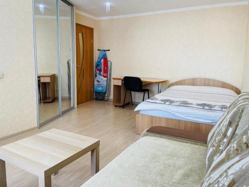 ウフタにあるАпартаменты на Ленинаのベッド、テーブル、椅子が備わるホテルルームです。
