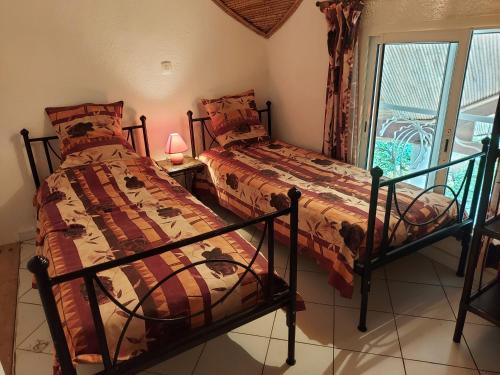 two beds in a room with a window at Villa Teranga in Saly Portudal