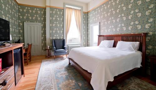 a bedroom with a bed and a tv and a chair at Oneida Community Mansion House in Oneida