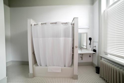 a white bathroom with a shower and a sink at Oneida Community Mansion House in Oneida