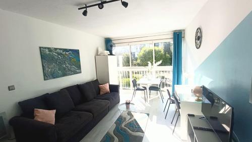 un salon avec un canapé noir et une table dans l'établissement Studio 26m2 centre ville rénové avec parking privé, à La Grande Motte