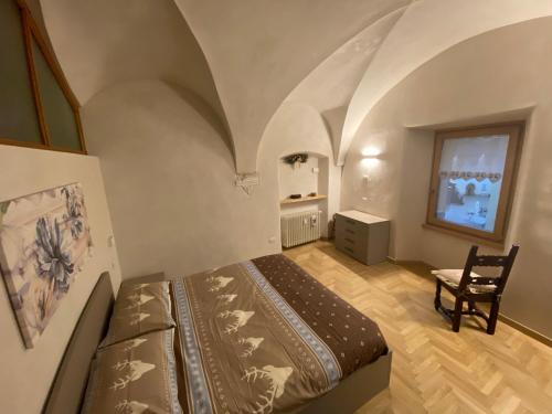ein Schlafzimmer mit einem Bett und einem Stuhl in einem Zimmer in der Unterkunft Appartamento Cavour in Bormio