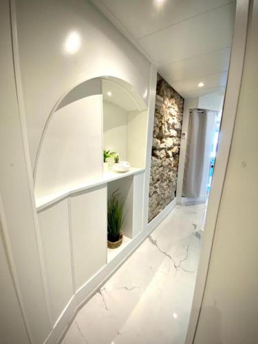 La salle de bains blanche est pourvue d'un miroir et d'un mur en pierre. dans l'établissement LE ROCAMARE -Superb-Atypical Sea view-A.C-WIFI, à Nice