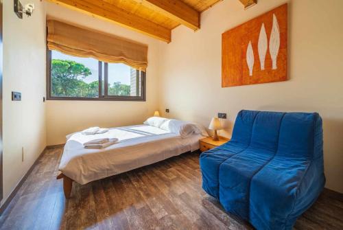 a bedroom with a bed and a blue chair at Villa Mestres Playa de Aro in Platja  d'Aro