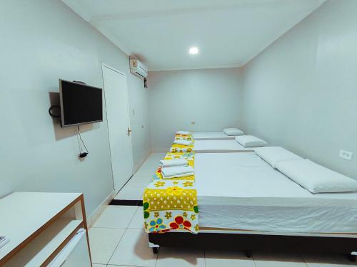 a room with four beds and a flat screen tv at Barra Nova Hotel in Saloá