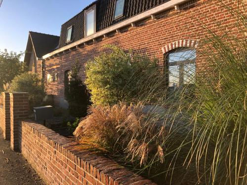 a brick house with a retaining wall and plants at Aux Herbes Hautes in Fleurbaix