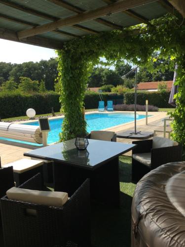 a patio with tables and chairs next to a pool at La Chambre des Amis in Parthenay