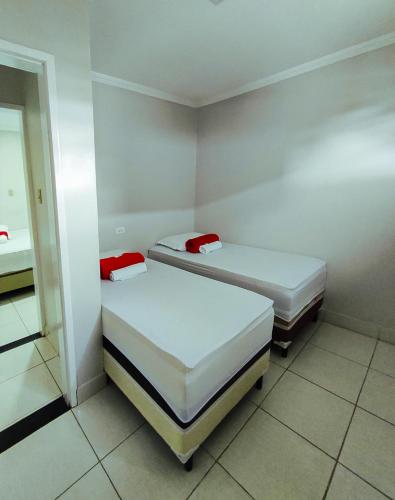 two beds in a small room with white walls at Barra Nova Hotel in Saloá