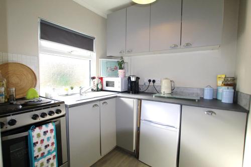 een keuken met witte kasten en een fornuis met oven bij Peaceful Garden Apartment in Herne Bay