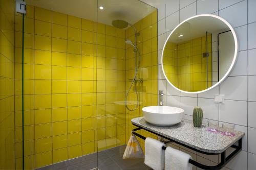 a yellow tiled bathroom with a sink and a mirror at ibis Styles Darmstadt in Darmstadt