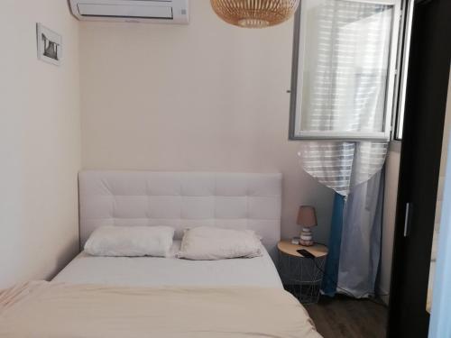 un lit blanc dans une chambre avec une fenêtre dans l'établissement Appartement avec terrasse, à Saint Cyprien Plage