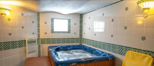 a blue tub in a green and white tiled bathroom at Penzión Encián in Tatranská Lomnica
