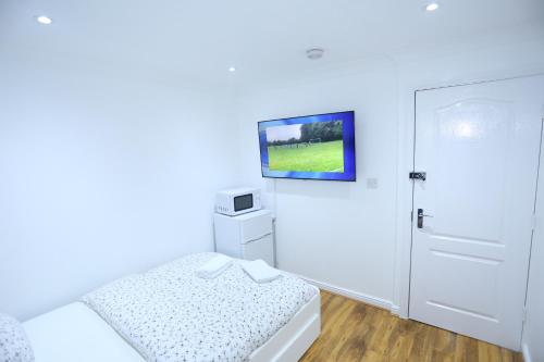 ThamesmeadにあるCosy Room with en-suite bathroom and shared kitchenの白い部屋(ベッド1台、壁掛けテレビ付)