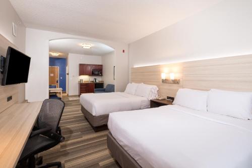 a hotel room with two beds and a flat screen tv at Holiday Inn Express Hotel & Suites Grand Blanc by IHG in Grand Blanc