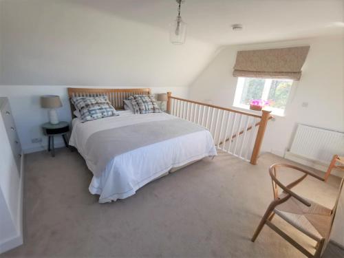 ein Schlafzimmer mit einem Bett und einem Stuhl und einem Fenster in der Unterkunft Contemporary Cottage outside South Harting in South Harting