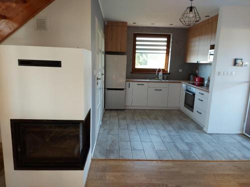 a kitchen with white cabinets and a tile floor at Domek Rospuda in Rospuda