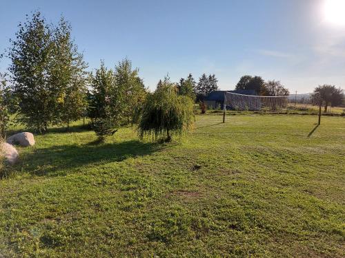 a field of grass with a fence and trees at Domek Rospuda in Rospuda
