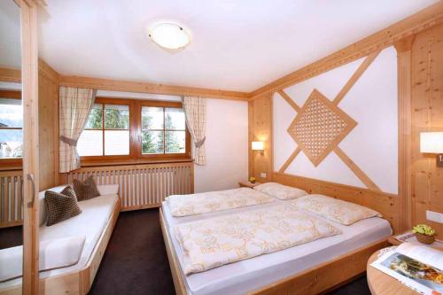een slaapkamer met 2 bedden en een tafel en ramen bij Grohmann Apartments in Selva di Val Gardena