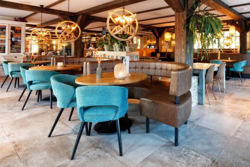 a restaurant with wooden tables and blue chairs at Hotel De Walvisvaarder in Lies