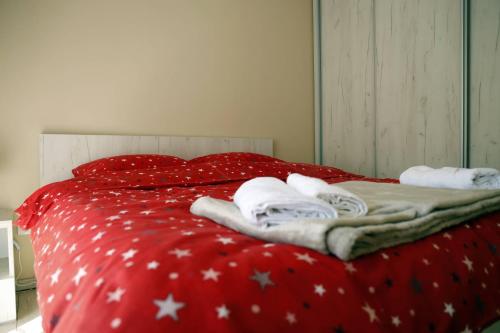 a red bed with white blankets and towels on it at Apartment Alexandar in Podgorica